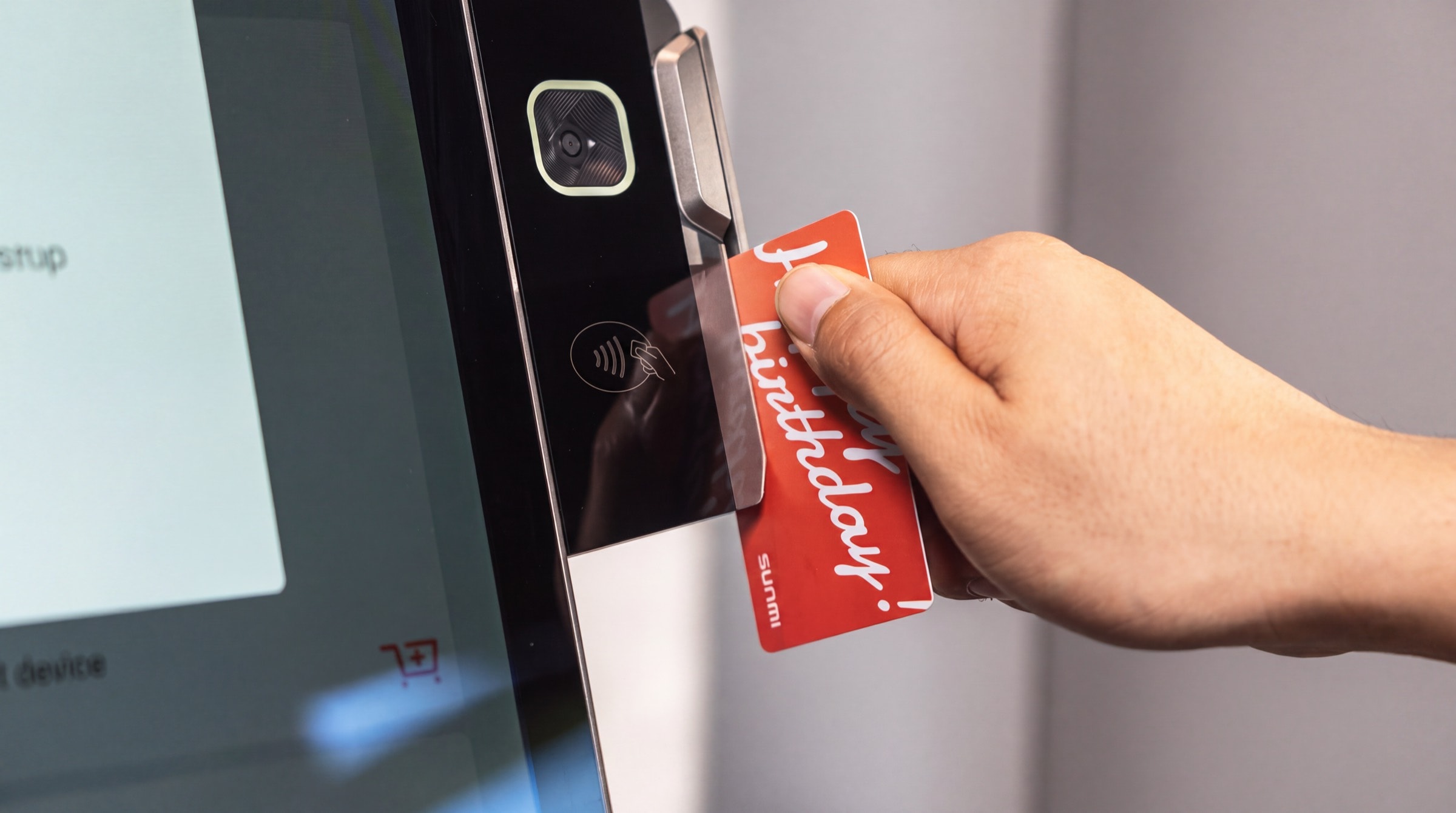 A hand holding a card to the contactless reader on the head of a kiosk