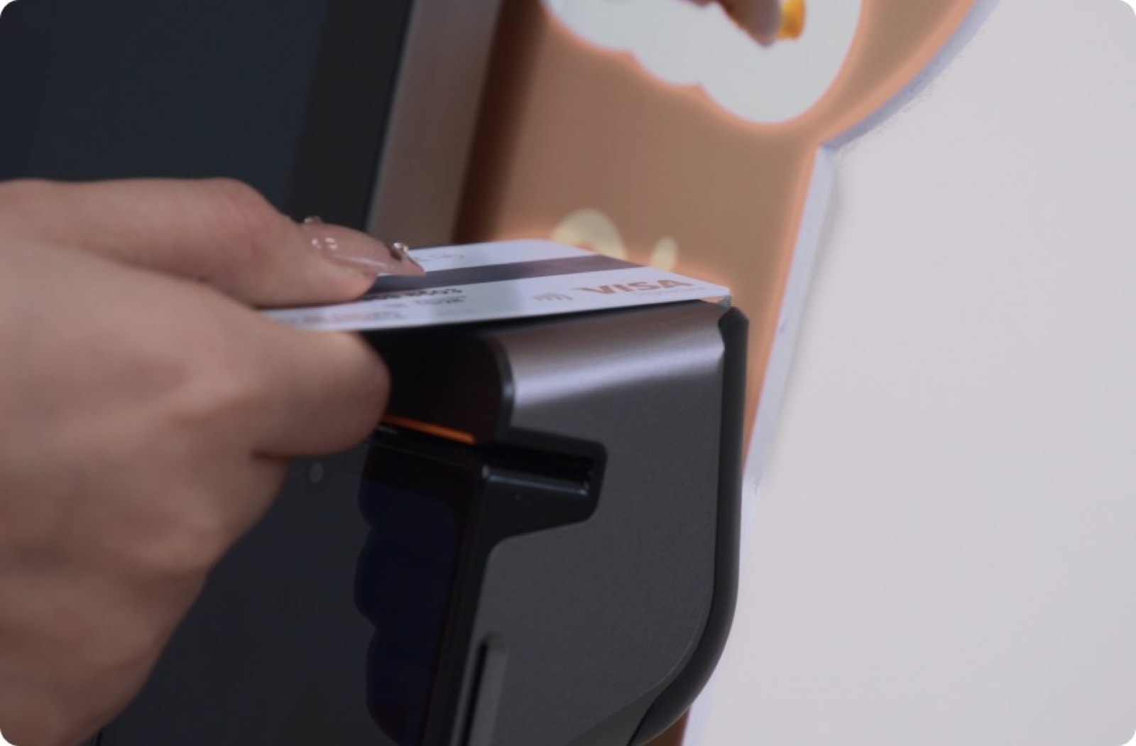 A card held to the payment terminal clipped to the side of a kiosk