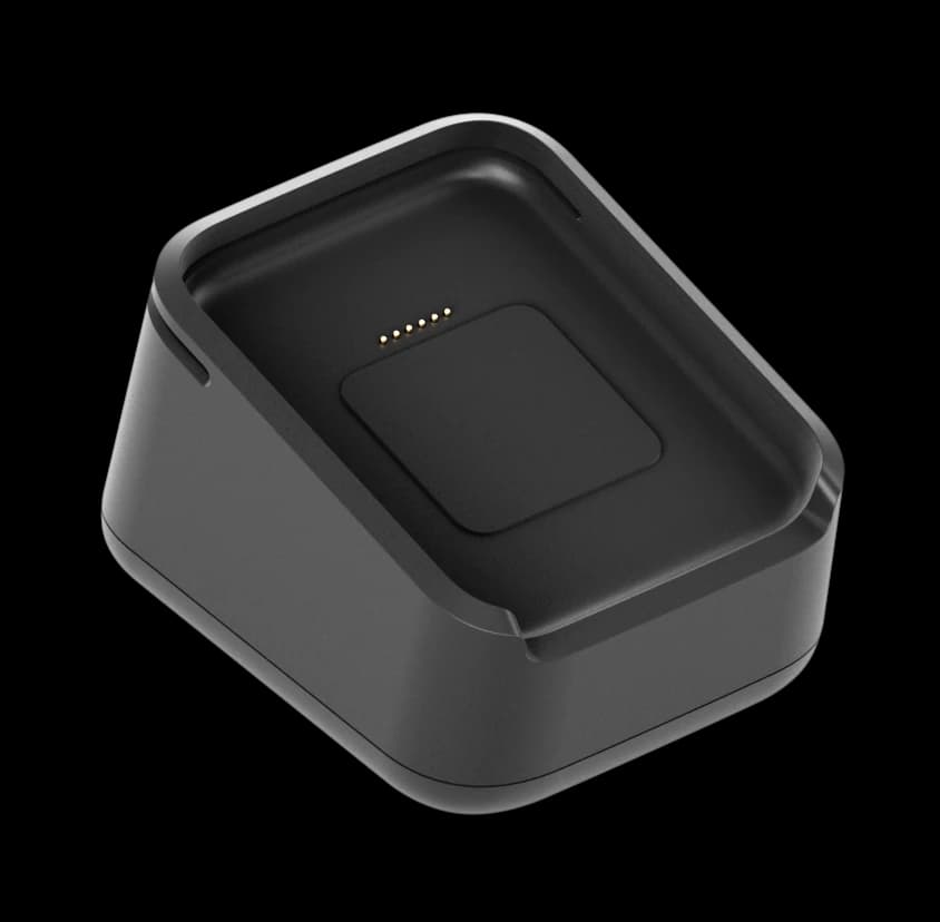 The dock seen from above at an angle: a squat black cradle with a shaped well and gold charging contacts where the reader sits