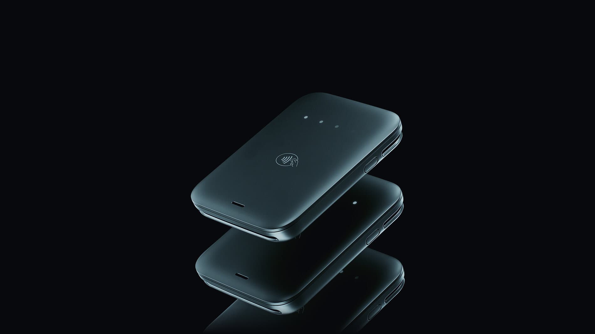 The Final Move reader seen from above at an angle, floating over its own reflection on a black surface, the contactless mark and the status lights visible on its face
